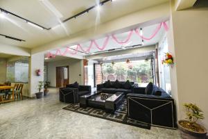sala de estar con sofás negros y mesa en FabHotel Naina Residency en Rāiwāla