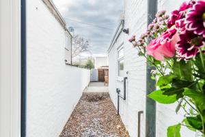 a pathway between two buildings with pink flowers at Modern 2 Bedroom Flat - Short Walk From The Station in Cambridge