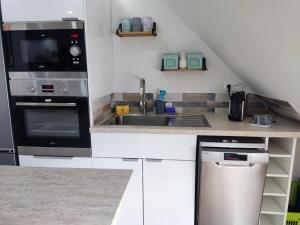 cocina blanca con fregadero y microondas en Chez Soline - Le Duplex climatisé en Amboise
