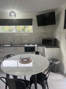 La cocina está equipada con mesa, sillas, mesa y mesa. en Batemans Bay North Bush Cottages, en Benandarah