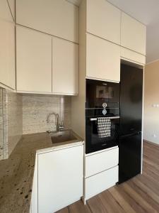 a kitchen with white cabinets and a black refrigerator at AgaApartments in Słupca