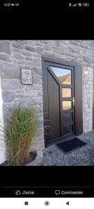 une porte menant à un bâtiment en pierre avec un panneau. dans l'établissement Le P'tit Nid : Mini loft pour 2 à 4 personnes, à Tellin