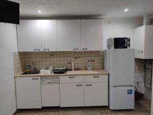 a kitchen with white cabinets and a white refrigerator at Csalogány Villa Balatonboglár in Balatonboglár