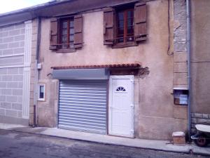 a building with a garage door and a white door at Village où il fait bon de vivre in Mauléon-Barousse