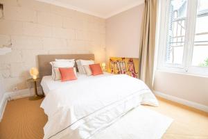 een wit bed in een kamer met een groot raam bij The cosy nest in the heart of Amboise in Amboise