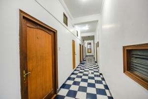 a hallway with a checkered floor and a wooden door at FabHotel Prime Hemkunth in Kasauli
