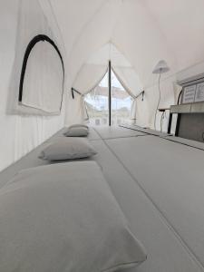 Cette chambre blanche comprend un lit et un miroir. dans l'établissement The Coco Journey - Eco Tent, à Kelebang Besar