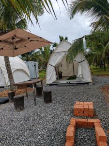 un gruppo di tende con tavolo e ombrellone di The Coco Journey - Eco Tent a Kelebang Besar