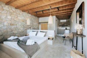 a bedroom with a large bed and a stone wall at White and Grey 2 in Mikonos