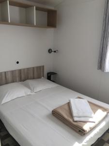 - un lit blanc avec 2 serviettes dans l'établissement Camping Milella, à Propriano