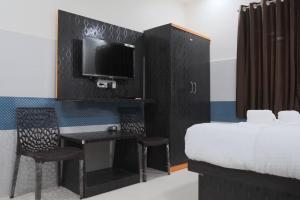 Habitación con cama, escritorio y TV. en Hotel Kalpesh, en Navi Mumbai