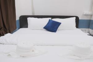 Una cama blanca con una almohada azul. en Hotel Kalpesh, en Navi Mumbai