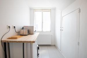 a white kitchen with a wooden counter and a window at Le Petit Marais in Amboise