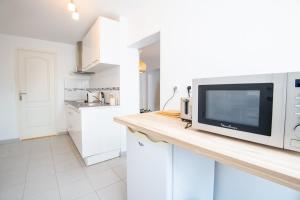 a white kitchen with a counter with a microwave at Le Petit Marais in Amboise