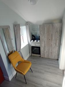 a yellow chair in a room with a kitchen at Tiernan's luxury triple room Ensuite in Charlestown