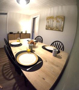 uma mesa de madeira com cadeiras e pratos em Orange Squirrel Lodge em Aviemore