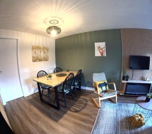 uma sala de jantar com uma mesa e cadeiras e uma televisão em Orange Squirrel Lodge em Aviemore