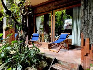 - deux chaises bleues assises sur une terrasse dans l'établissement Udara Bali Yoga Detox & Spa, à Canggu