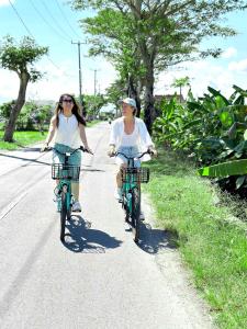 two women riding bikes down a road at Udara Bali Yoga Detox & Spa in Canggu