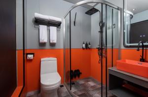 La salle de bains orange est pourvue d'une douche et de toilettes. dans l'établissement Banana Fun Hotel - Guangzhou East Railway Station Yantang Metro Station, à Canton