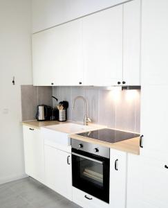 - une cuisine avec des placards blancs et un évier dans l'établissement Ferienwohnung Charlotte, à Glücksburg