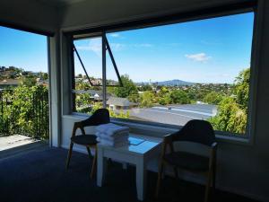 um quarto com duas cadeiras e uma mesa em frente a uma janela em Sunshine hillcrest home em Auckland