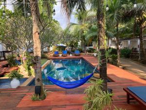 una hamaca colgada entre dos palmeras junto a una piscina en Isle Beach Resort Krabi-SHA en Klong Muang Beach