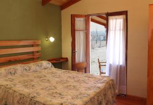 a bedroom with a bed and a sliding glass door at Cabañas El Quijote in Los Reartes +59 photos
