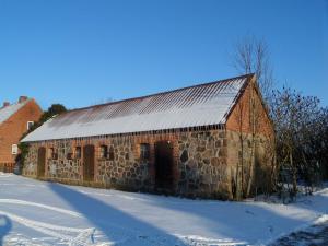 a red brick barn with a metal roof in the snow at Doppelhaushälfte in idyllischer Lage, separater Eingang in Reimershagen