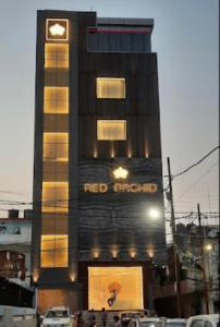 un edificio alto con un letrero rojo bajo tierra. en Red Orchid Hotel Kanpur, en Kānpur