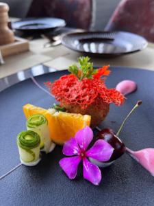 un plato azul cubierto con fruta y flores en una mesa en Red Orchid Hotel Kanpur, en Kānpur