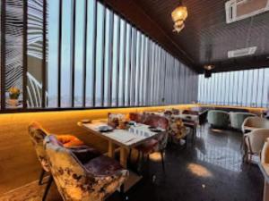 un restaurante con mesas y sillas y una gran ventana en Red Orchid Hotel Kanpur, en Kānpur