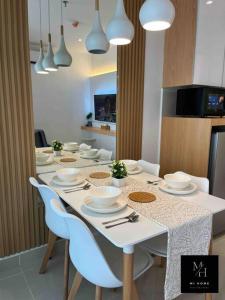 a dining room table with white plates and chairs at The Shore Kota Kinabalu by MiHome in Kota Kinabalu