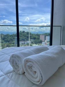 a bed with white sheets and a view of a city at The Shore Kota Kinabalu by MiHome in Kota Kinabalu