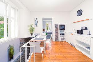 cocina con armarios blancos, mesa y sillas en Komló Apartman - Mátyás, en Kőszeg