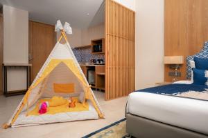 The Astor - All Suites Hotel Candolim Goa في كاندوليم: غرفة نوم فيها خيمة لعب فيها العاب