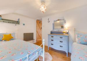 sypialnia z łóżkiem, komodą i lustrem w obiekcie Spray Cottage w mieście Saint Ervan