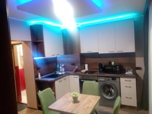 a kitchen with a table and a blue light at Кръчмъ При Байката апарт in Teteven