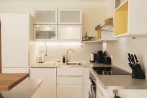 a white kitchen with white cabinets and a sink at ALPSTAY "Platzhirsch" - XL Garten, Gondelnähe & Netflix in Bad Kleinkirchheim