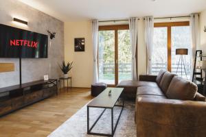 a living room with a couch and a tv at ALPSTAY "Platzhirsch" - XL Garten, Gondelnähe & Netflix in Bad Kleinkirchheim