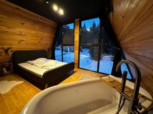 ein Bad mit Badewanne und ein Bett in einem Zimmer in der Unterkunft Black Chalet in Vartop