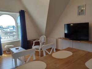 een woonkamer met een tv en een tafel en stoelen bij Le Repaire de l'Armateur in Granville