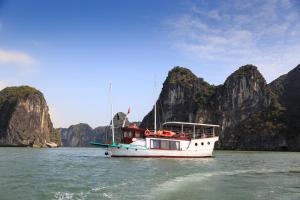 un barco en el agua con montañas en el fondo en Emeraude Classic Cruises, en Ha Long