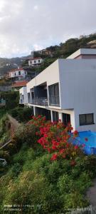 a white house with red flowers in front of it at D Henriques House in Câmara de Lobos