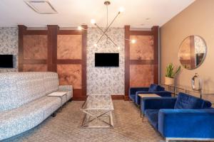 a living room with blue couches and a tv at Sandman Hotel Edmonton West in Edmonton