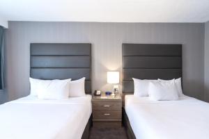 duas camas num quarto de hotel com almofadas brancas em Sandman Hotel Edmonton West em Edmonton