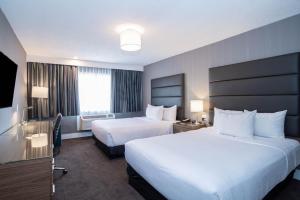 una camera d'albergo con 2 letti e una scrivania di Sandman Hotel Edmonton West a Edmonton