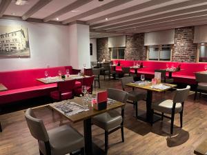 ein Restaurant mit roten Nischen, Tischen und Stühlen in der Unterkunft Gasterij Berg en Dal in Slenaken