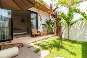 a patio with a garden with a bed and a table at Karma House Ungasan in Jimbaran