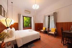 a bedroom with a bed and a desk and a chair at Hoianese Heritage Hotel - Truly Hoi An in Hoi An